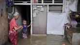 Seorang nenek menuntun cucunya di depan rumahnya yang terendam banjir di Jalan Anyer, Menteng, Jakarta, Minggu (23/2). Menurut warga, sedikitnya 14 RT di lingkungan RW 02 rumahnya terendam banjir akibat tingginya intensitas hujan dan buruknya drainase. (ANTARA FOTO/M Risyal Hidayat)