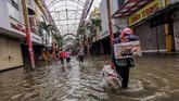 Warga melintasi banjir menggenangi pertokoan Pasar Baru, Jakarta Pusat, Selasa (25/2/2020). ANTARAFOTO/Fanny Octavianus.