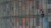 Seperti aksi Robert sebelumnya, kali ini ia memanjat gedung pencakar langit di Barcelona dengan tangan kosong alias tanpa pengaman. (Photo by LLUIS GENE / AFP)