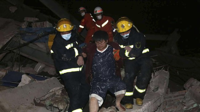 Tim penyelamat membantu pria keluar dari reruntuhan hotel di Quanzhou, China. Hotel yang digunakan sebagai tempat karantina virus corona tersebut ambruk Sabtu (7/3). (Chinatopix via AP).