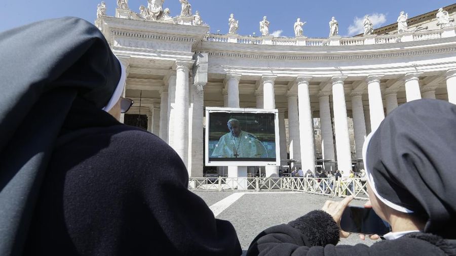 Nuns and faithful watch Pope Francis deliver the Angelus prayer on a giant screen, in St. Peter's Square, at the Vatican, Sunday, March 8, 2020. Italy's Prime Minister Giuseppe Conte announced a sweeping coronavirus quarantine early Sunday, restricting the movements of about a quarter of the country's population in a bid to limit contagions at the epicenter of Europe's outbreak. (AP Photo/Andrew Medichini)