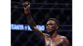 Israel Adesanya merayakan kemenangan atas Yoel Romero setelah dinyatakan menang oleh juri usai pertarungan lima ronde. (Harry How/Getty Images/AFP)