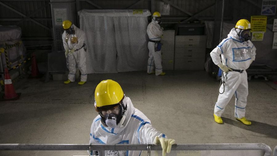 In this Feb. 12, 2020, photo, workers in hazmat suits take a break at a water treatment facility at the Fukushima Dai-ichi nuclear power plant in Okuma, Fukushima Prefecture, Japan. Nine years ago, on March 11, 2011, a magnitude 9.0 quake and tsunami destroyed key cooling functions at the plant, causing a meltdown that leaked a massive amount of radiation and forcing some 160,000 residents to evacuate. About 40,000 of them still haven't returned. (AP Photo/Jae C. Hong)