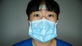 Tim perawat terdiri dari orang-orang yang bekerja penuh dan paruh waktu. Perban di wajah mewakili upaya mereka membantu para korban virus corona. (Photo by Ed JONES / AFP)