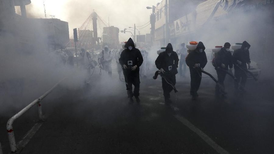Petugas kebakaran di Iran berjibaku membersihkan jalan-jalan di Iran untuk mencegah bertambahnya korban akibat Covid-19.