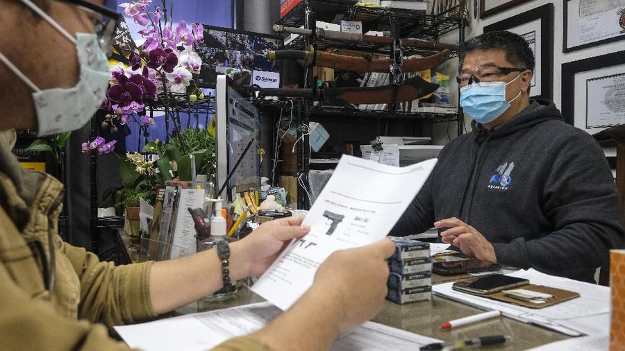 David Liu, right, owner of a gun store, takes an order from a customer in Arcadia, Calif., Sunday, March 15, 2020. Coronavirus concerns have led to consumer panic buying of grocery staples and now gun stores are seeing a run on weapons and ammunition as panic intensifies. (AP Photo/Ringo H.W. Chiu)
