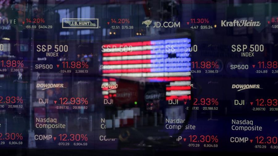 A United States flag is reflected in the window of the Nasdaq studio, which displays indices and stocks down, in Times Square, New York, Monday, March 16, 2020. (AP Photo/Seth Wenig)
