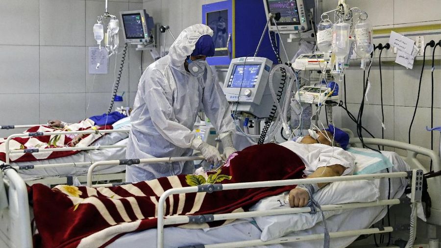 In this Sunday, March 1, 2020 photo, a medic treats a patient infected with coronavirus, at a hospital in Tehran, Iran. A member of a council that advises Iran's supreme leader died Monday after falling sick from the new coronavirus, becoming the first top official to succumb to the illness striking both citizens and leaders of the Islamic Republic. (Ali Shirband/Mizan News Agency via AP)