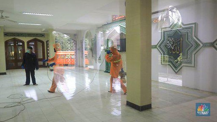 Petugas tata lingkungan Taman Mini Indonesia Indah menyemprotkan cairan disinfektan.