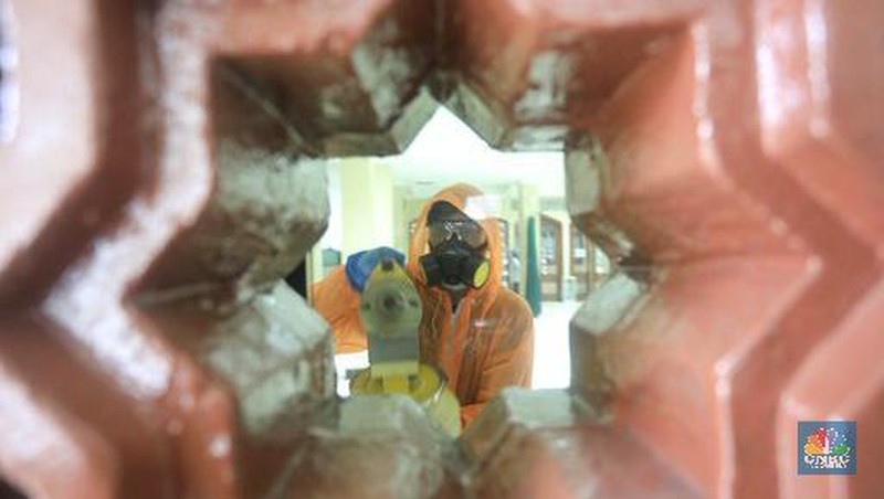 Petugas tata lingkungan Taman Mini Indonesia Indah menyemprotkan cairan disinfektan.