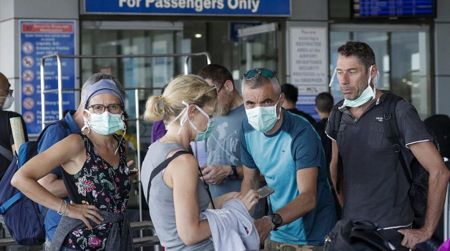 Foreigners wearing protective masks prepare to enter the departure area of Manila's International Airport, Philippines on Wednesday, March 18, 2020. The Philippine government lifted a 72-hour deadline for thousands of foreign travelers to leave the country's main northern region which has been placed under quarantine due to the growing number of coronavirus infections, officials said. For most people, the new coronavirus causes only mild or moderate symptoms. For some, it can cause more severe illness, especially in older adults and people with existing health problems. (AP Photo/Joeal Calupitan)