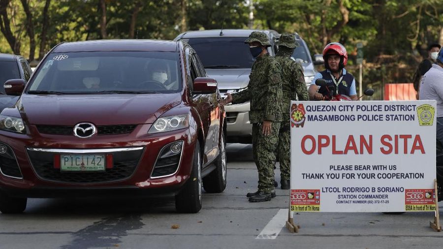 Police stop motorists at a checkpoint in Metro Manila, Philippines on Wednesday, March 18, 2020. The Philippine government lifted a 72-hour deadline for thousands of foreign travelers to leave the country's main northern region which has been placed under quarantine due to the growing number of coronavirus infections, officials said. For most people, the new coronavirus causes only mild or moderate symptoms. For some, it can cause more severe illness, especially in older adults and people with existing health problems. (AP Photo/Joeal Calupitan)