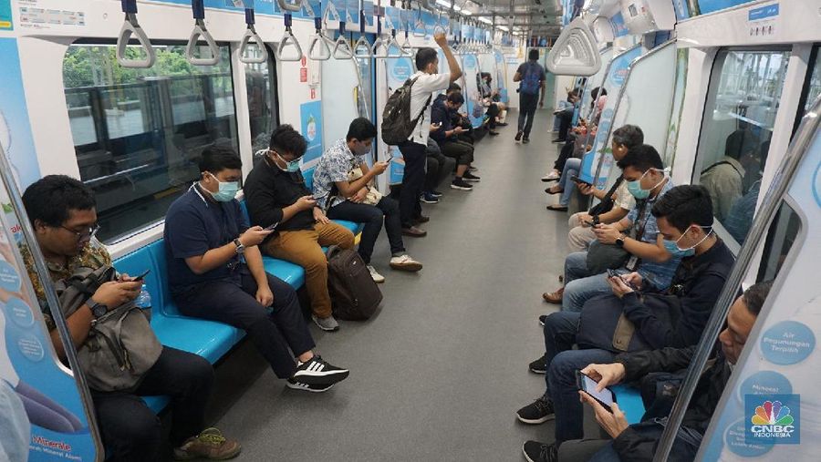 Pengunjung MRT duduk di bangku yang telah diberi stiker panduan jarak 