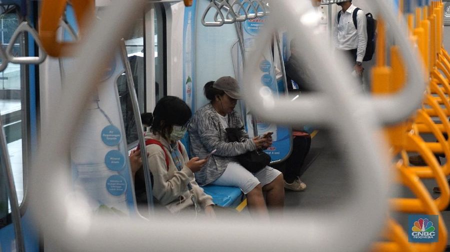 Pengunjung MRT duduk di bangku yang telah diberi stiker panduan jarak 