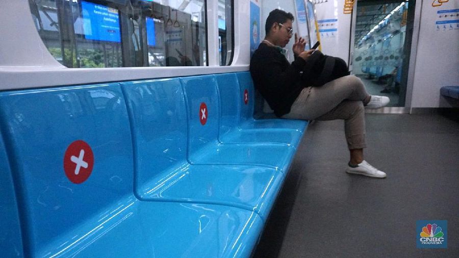 Pengunjung MRT duduk di bangku yang telah diberi stiker panduan jarak 