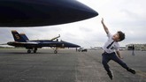 Micha Robbins, 4, mencoba menyentuh F/A-18 Hornet Blue Angel sesaat setelah tim Angkatan Laut Amerika Serikat mendarat di Waco, Texas, untuk mengii bahan bakar. (Jerry Larson/Waco Tribune-Herald via AP)