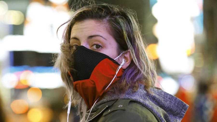 Brooklyn resident and waitress Casey Stewart peers out from a ski mask she adapted to protect herself from coronavirus after riding the subway to Times Square, Thursday, March 12, 2020, in New York to see for herself the virus outbreak's effect on the city. She is also wearing a protective mask beneath the ski mask. Stewart, who works at two restaurants, said she's definitely noticed a drop in the number of customers. She's also concerned because at least one of the places she works may have to close for at least a week or possibly longer. (AP Photo/Kathy Willens)