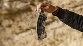 Barang-barang berupa magasin masih berserakan di ladang petani di Baghouz. (Photo by DELIL SOULEIMAN / AFP)