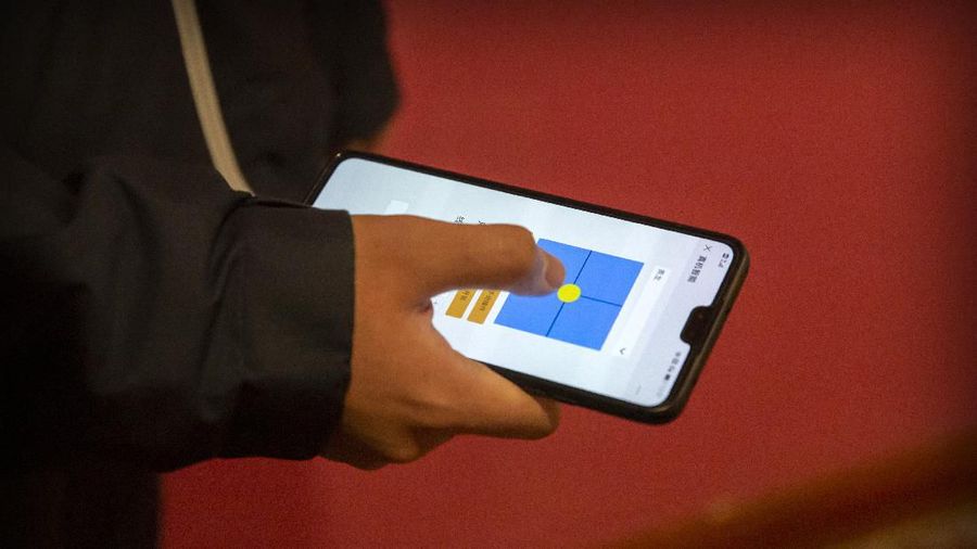 In this March 18, 2020, photo, a worker uses a smartphone app to guide a robot at the offices of ZhenRobotics in Beijing. While other industries struggle, one robot maker says China's virus outbreak is boosting demand for his knee-high, bright yellow robots to deliver groceries and patrol malls for shoppers who fail to wear masks. (AP Photo/Mark Schiefelbein)