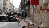 Seorang pria berjalan melewati kendaraan yang rusak tertimpa reruntuhan. Gempa ini membuat warga panik dan berhamburan ke luar rumah dan bangunan. (AP Photo/Darko Bandic)