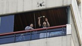 Seorang perempuan di balkonnya mengambil bunga yang diantarkan lewat drone. Saat ini masyarakat Libanon telah lebih dari satu pekan menjalani masa karantina di rumah. (Photo by JOSEPH EID / AFP)