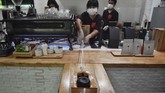 Untuk mengatasi rasa takut, para pegawai di Art of Coffee ini menerapkan jarak aman 1 meter dari pelanggan. Mereka pun memutar otak untuk bisa memberikan kopi dan uang kembalian dengan cara yang aman. (Lillian SUWANRUMPHA / AFP)