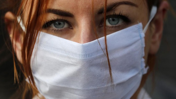 An member of the group 'Pause the System' wears a face mask as she protests in front of the entrance to Downing Street in London, Friday, March 20, 2020. For most people, the new coronavirus causes only mild or moderate symptoms, such as fever and cough. For some, especially older adults and people with existing health problems, it can cause more severe illness, including pneumonia. (AP Photo/Frank Augstein)