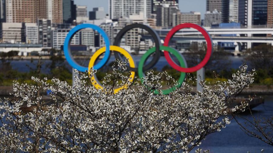 The Olympic rings floating on a barge are seen behind cherry blossoms Wednesday, March 25, 2020, in the Odaiba section of Tokyo. Not even the Summer Olympics could withstand the force of the coronavirus. After weeks of hedging, the IOC took the unprecedented step of postponing the world's biggest sporting event, a global extravaganza that's been cemented into the calendar for more than a century. (AP Photo/Jae C. Hong)