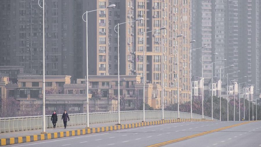 People wearing face masks walk down a deserted street in Wuhan in central China's Hubei Province, Tuesday, Jan. 28, 2020. China's death toll from a new viral disease that is causing a  global concern rose by 25 to at least 106 on Tuesday as the United States and other governments prepared to fly their citizens out of the locked-down city at center of the outbreak. (AP Photo/Arek Rataj)