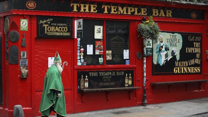 A man dressed as St Patrick walks past a closed Temple bar in Dublin city centre, Monday, March, 16, 2020. All pubs in the Republic of Ireland closed late Sunday to try and tackle the spread of Covid-19. For most people, the new coronavirus causes only mild or moderate symptoms. For some it can cause more severe illness, especially in older adults and people with existing health problems.(AP Photo/Peter Morrison)