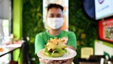 Menurut sang pemilik restoran, Hoang Tung, varian burger ini dikeluarkan agar masyarakat tak lagi takut pada pandemi corona. Ia menamainya coronaburger. (Manan VATSYAYANA / AFP)