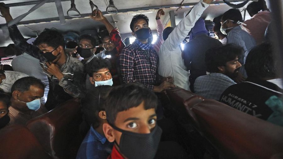 Migrant daily wage laborers crowd a bus as they travel to their hometowns following a lockdown amid concerns over the spread of the COVID-19 coronavirus in New Delhi, India, Friday, March 27, 2020. Some of India's legions of poor and others suddenly thrown out of work by a nationwide stay-at-home order began receiving aid on Thursday, as both public and private groups worked to blunt the impact of efforts to curb the pandemic. The measures that went into effect Wednesday, the largest of their kind in the world, risk heaping further hardship on the quarter of the population who live below the poverty line and the 1.8 million who are homeless. (AP Photo/Manish Swarup)