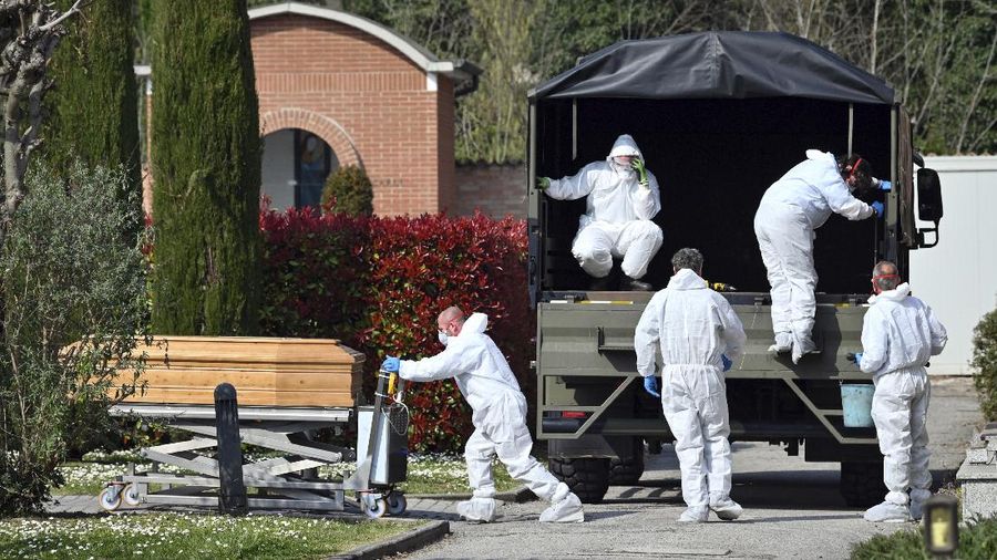 A convoy of Italian Army trucks is unloaded upon arrival from Bergamo carrying bodies of coronavirus victims to the cemetery of Ferrara, Italy, where they will be cremated, Saturday, March 21, 2020. The transfer was made necessary since Bergamo mortuary reached maximum capacity. For most people, the new coronavirus causes only mild or moderate symptoms. For some it can cause more severe illness, especially in older adults and people with existing health problems. (Massimo Paolone/LaPresse via AP)