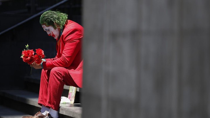 avid Vazquez, seorang penampil jalanan berpakaian seperti Joker (AP/Rebecca Blackwell) David Vazquez, a street performer dressed as the Joker, waits in hopes of pedestrians who will pay to take pictures with him in Mexico City, Monday, March 23, 2020. Vazquez, who also worked as a trainer in a gym until it shut down today, said business for street performers has plummeted, with the few clients still stopping opting to take their pictures from a distance or posing beside him awkwardly, amid the worldwide spread of the new coronavirus.