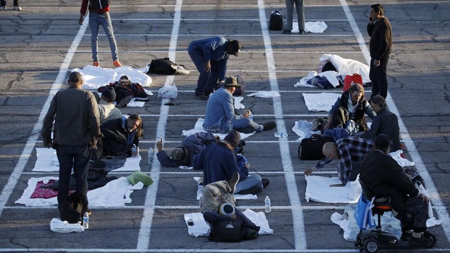 People prepare places to sleep at a makeshift camp for the homeless Monday, March 30, 2020, in Las Vegas. Officials opened part of a parking lot as a makeshift homeless shelter after a local shelter closed when a man staying there tested positive for coronavirus. (AP Photo/John Locher)