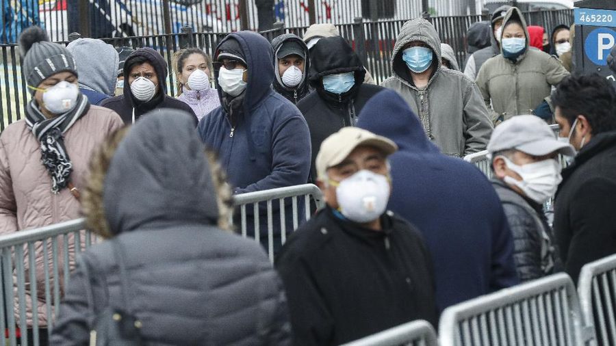 Patients wear personal protective equipment while maintaining social distancing as they wait in line for a COVID-19 test at Elmhurst Hospital Center, Wednesday, March 25, 2020, in New York. Gov. Andrew Cuomo sounded his most dire warning yet about the coronavirus pandemic Tuesday, saying the infection rate in New York is accelerating and the state could be as close as two weeks away from a crisis that sees 40,000 people in intensive care. Such a surge would overwhelm hospitals, which now have just 3,000 intensive care unit beds statewide. (AP Photo/John Minchillo)