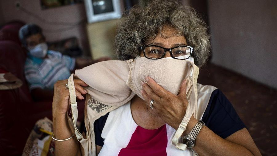 Idania Espanola, 63, poses for a photo showing a women's bra's, before adapting it to wear it as a mask, as a precaution against the spread of the new coronavirus in Cojimar, Cuba, east of Havana, Tuesday, March 31, 2020. Cuban authorities are requiring the use of masks for anyone outside their homes. (AP Photo/Ramon Espinosa)