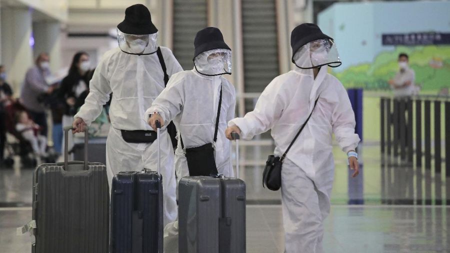 Passengers wear protective suits and face masks as they arrive at the Hong Kong airport, Monday, March 23, 2020. The new coronavirus causes mild or moderate symptoms for most people, but for some, especially older adults and people with existing health problems, it can cause more severe illness or death. (AP Photo/Kin Cheung)