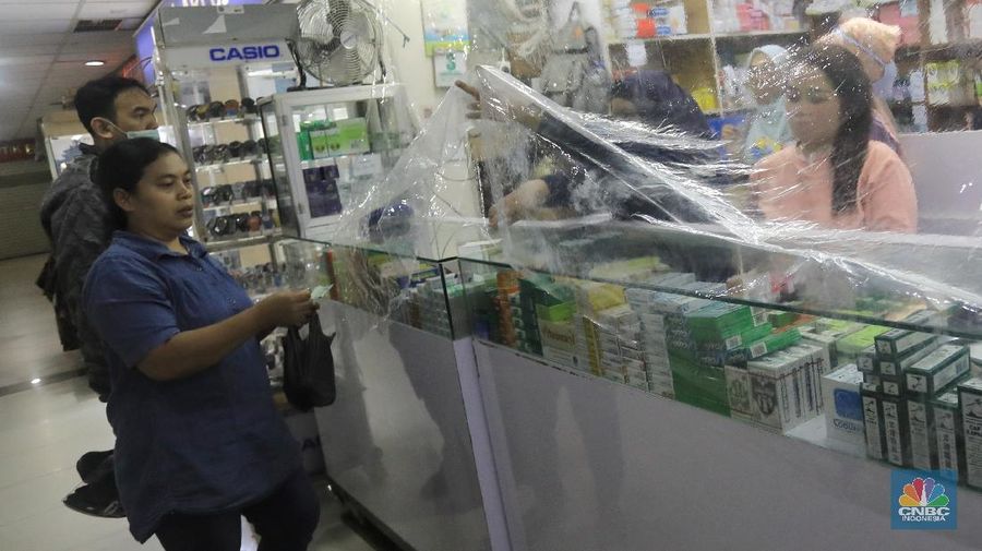 Begini penampakan toko Apotek di Pasar Baru, Jakarta, yang menutupi tokonya dengan tirai plastik untuk transaksi jual beli.