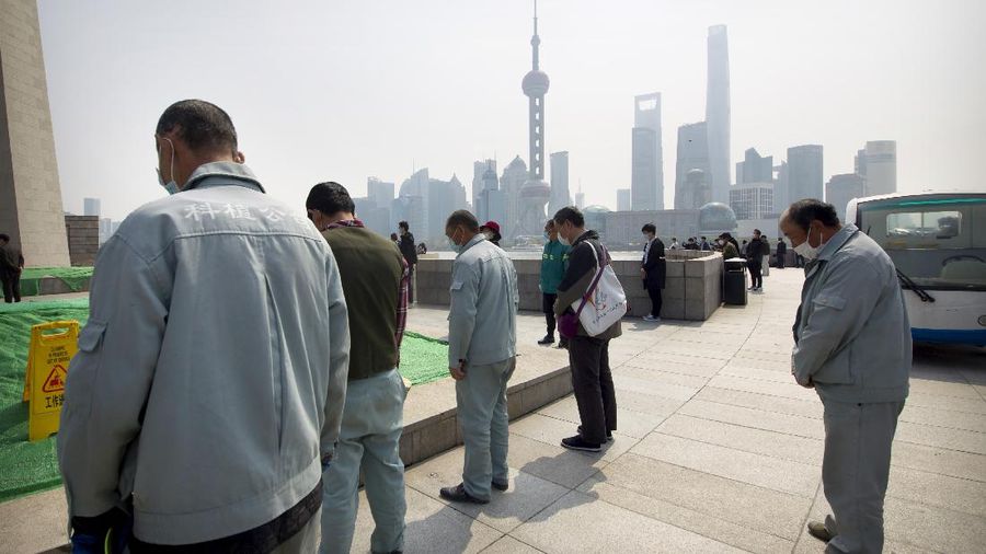 People bow their heads during a national moment of mourning for victims of coronavirus at the Bund in Shanghai, Saturday, April 4, 2020. With air raid sirens wailing and flags at half-staff, China on Saturday held a three-minute nationwide moment of reflection to honor those who have died in the coronavirus outbreak, especially 