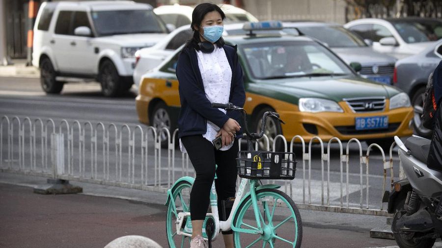 A cyclist pauses during a national moment of mourning for victims of the coronavirus, in Beijing on Saturday, April 4, 2020. With air raid sirens wailing and flags at half-staff, China on Saturday held a three-minute nationwide moment of reflection to honor those who have died in the coronavirus outbreak, especially 