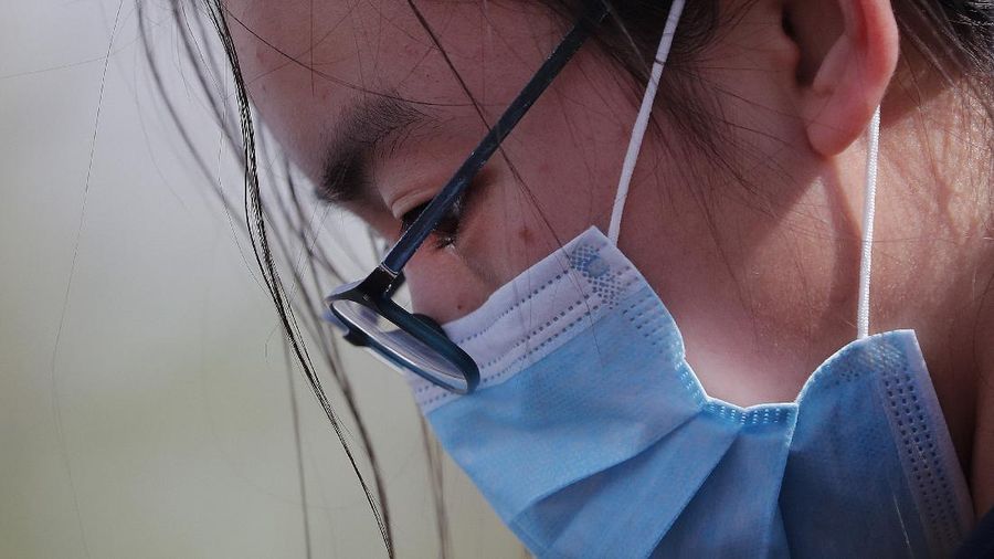 A woman wearing a protective face mask pauses during a national moment of mourning for victims of coronavirus near Tiananmen Square in Beijing, Saturday, April 4, 2020. With air raid sirens wailing and flags at half-mast, China on Saturday held a three-minute nationwide moment of reflection to honor those who have died in the coronavirus outbreak, especially 