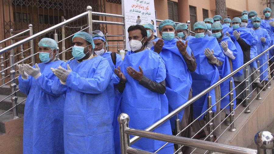 Hospital staff pray before joining their shift, outside a hospital setup for coronavirus infected patients in Quetta, Pakistan, Thursday, March 26, 2020. The virus causes mild or moderate symptoms for most people, but for some, especially older adults and people with existing health problems, it can cause more severe illness or death. (AP Photo/Arshad Butt)