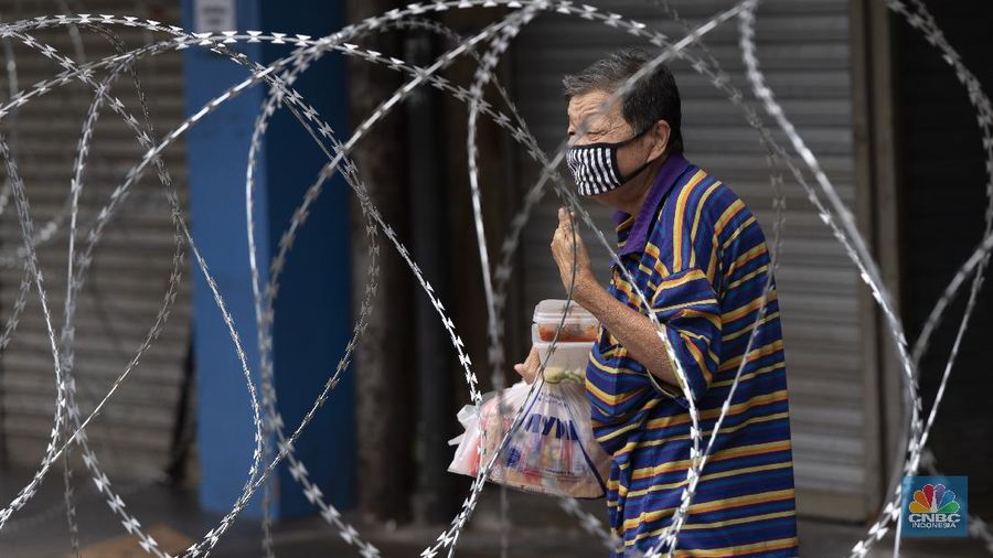 A resident collects a food delivery behind barbed wire outside a building under lockdown in downtown Kuala Lumpur, Malaysia, on Tuesday, April 7, 2020. The Malaysian government issued a restricted movement order to the public to help curb the spread of the new coronavirus. The new coronavirus causes mild or moderate symptoms for most people, but for some, especially older adults and people with existing health problems, it can cause more severe illness or death. (AP Photo/Vincent Thian)