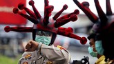 Anggota polisi dari Polres Mojokerto, Jawa Timur, mengenakan helm bentuk virus corona dalam aksi mengkampanyekan bahaya virus corona bagi masyarakat setempat. (AP Photo)