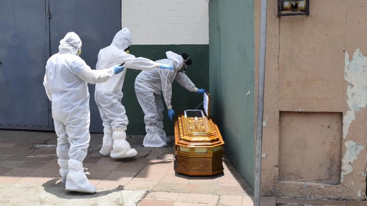 Korban Meninggal Akibat Covid-19 di Ekuador (AP/Edison Choco) A brigade wearing biohazard suits to protect themselves from the spread of the new coronavirus pick up a coffin with a body left outside a house in Guayaquil, Ecuador, Monday, April 6, 2020. Guayaquil, a normally bustling city that has become a hot spot in Latin America as the coronavirus pandemic spreads, also has untold numbers dying of unrelated diseases that can’t be treated because hospitals are overwhelmed. (AP Photo/Edison Choco)