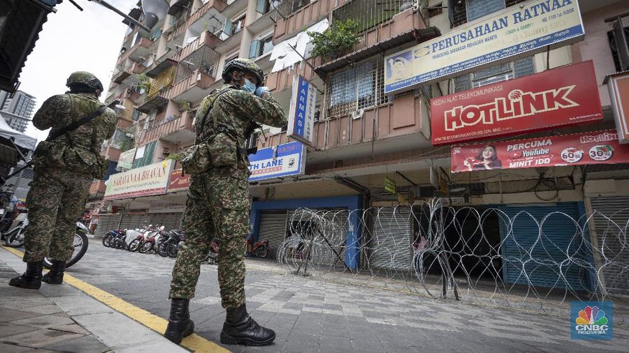 A resident collects a food delivery behind barbed wire outside a building under lockdown in downtown Kuala Lumpur, Malaysia, on Tuesday, April 7, 2020. The Malaysian government issued a restricted movement order to the public to help curb the spread of the new coronavirus. The new coronavirus causes mild or moderate symptoms for most people, but for some, especially older adults and people with existing health problems, it can cause more severe illness or death. (AP Photo/Vincent Thian)