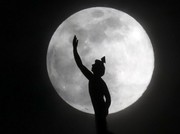 A supermoon rises behind a statue of the Roman god Mercury mounted on top of a hotel tower Tuesday, April 7, 2020, in Nashville, Tenn. (AP Photo/Mark Humphrey)
