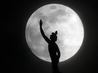 A supermoon rises behind a statue of the Roman god Mercury mounted on top of a hotel tower Tuesday, April 7, 2020, in Nashville, Tenn. (AP Photo/Mark Humphrey)