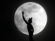A supermoon rises behind a statue of the Roman god Mercury mounted on top of a hotel tower Tuesday, April 7, 2020, in Nashville, Tenn. (AP Photo/Mark Humphrey)